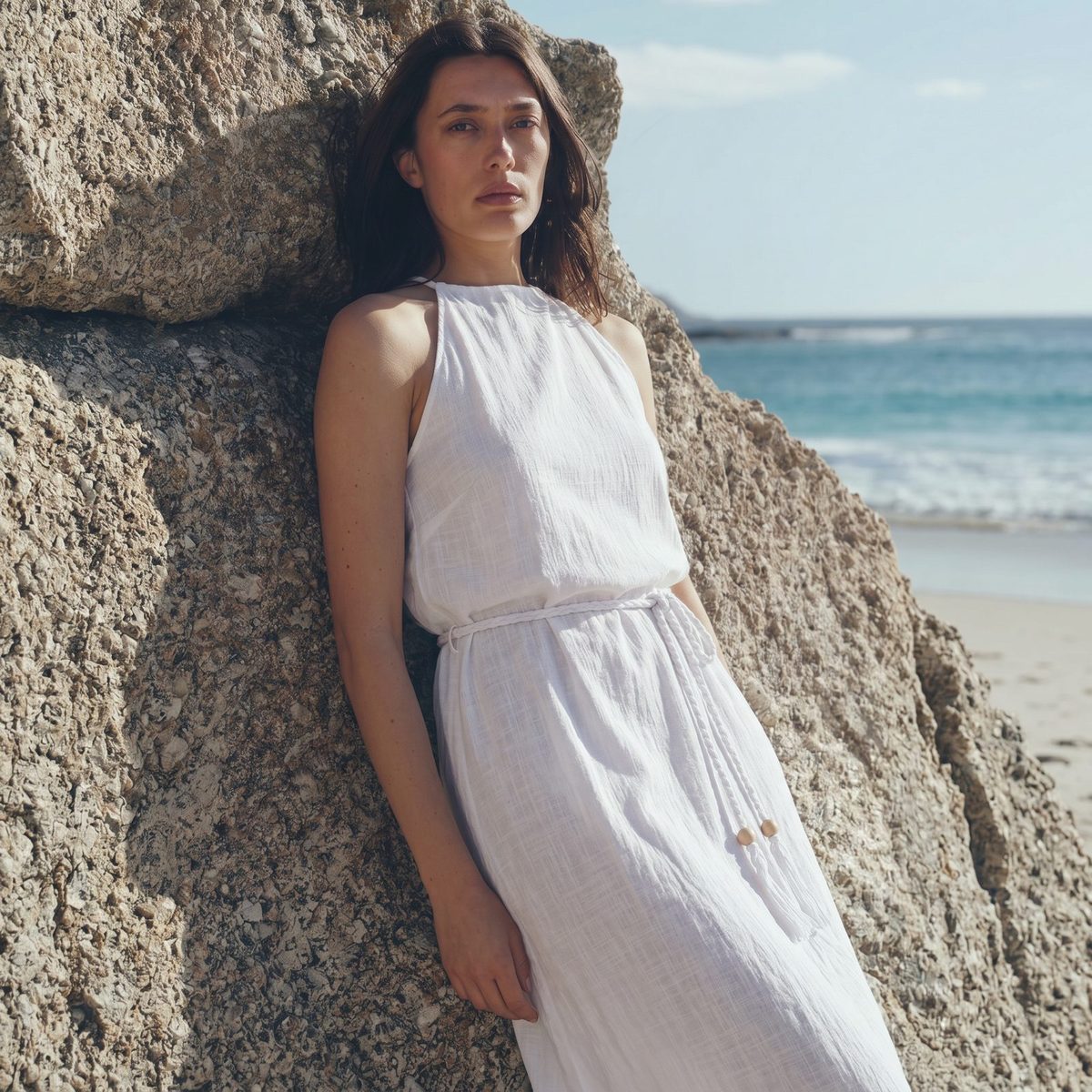 Woman in white linen set against a rock, generated scene